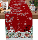 Un chemin de table décoré de motifs de Noël avec des gnomes, des flocons de neige et des branches d'arbres enneigés sur un fond rouge.
