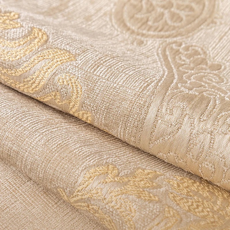 Le tissu richement texturé présente des motifs floraux et des dessins abstraits aux nuances dorées, offrant une sensation de luxe et d'élégance.