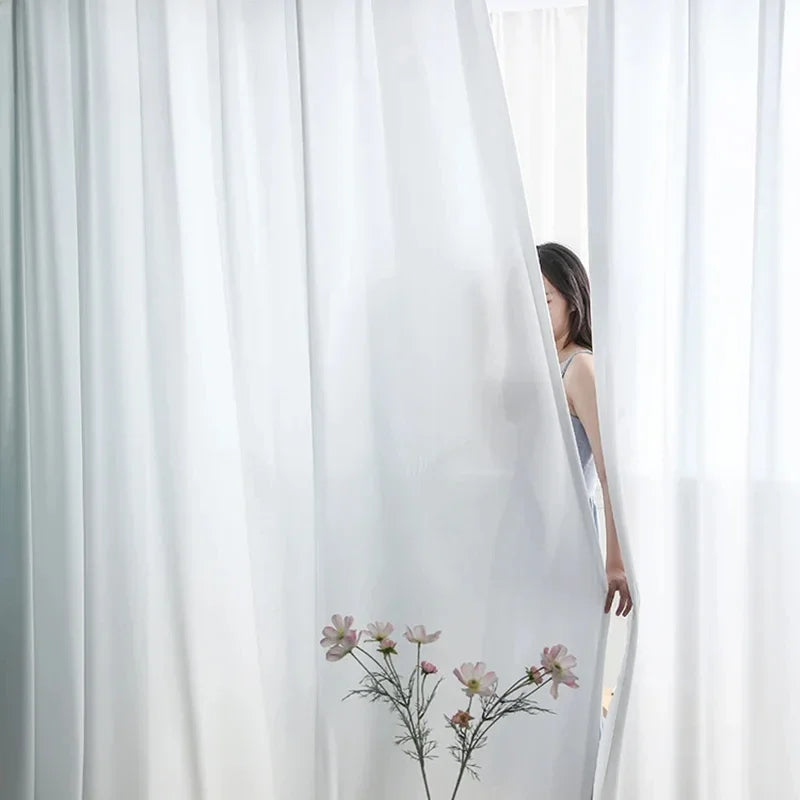 Voile de rideau blanc élégant pour salon moderne, offrant une ambiance lumineuse et délicate. Idéal pour créer un espace intime et épuré dans votre intérieur. Ajoutez une touche de sophistication à votre décoration tout en préservant la luminosité naturelle.