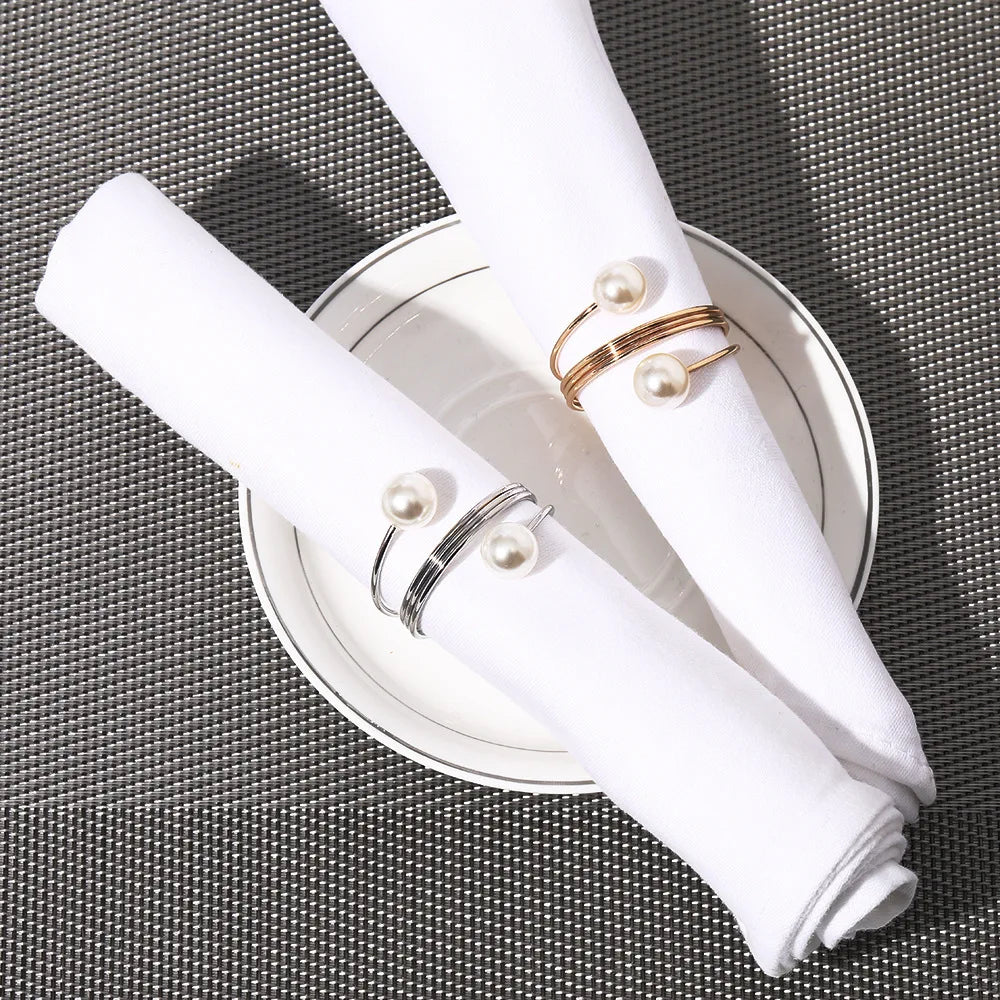 Arrangement élégant de bracelets et serviette blanche sur assiette métallique sur fond texturé noir et blanc.