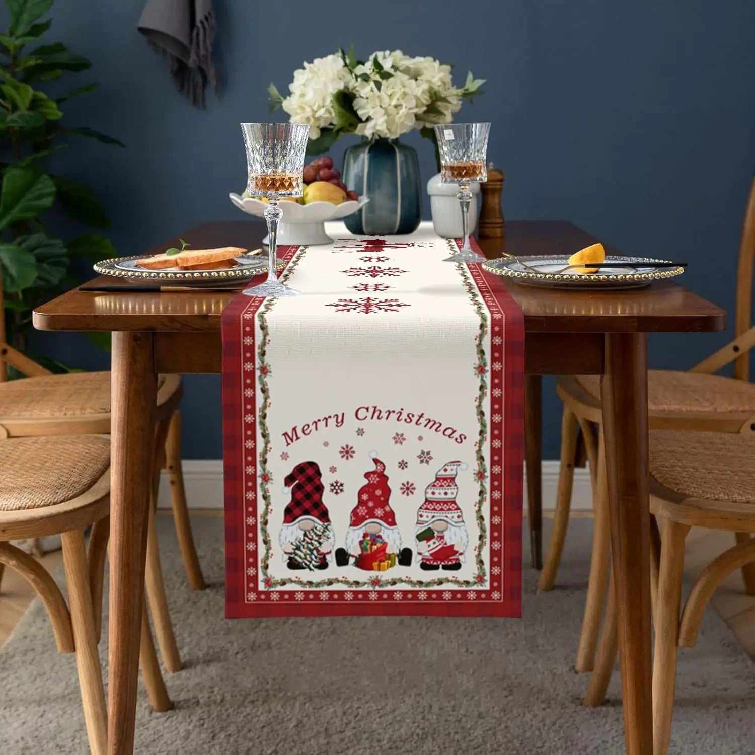 Cette table festive est parée pour Noël, avec un chemin de table décoré de motifs de gnomes et de flocons de neige, accompagnée d'un beau bouquet de fleurs et de verres à vin remplis.