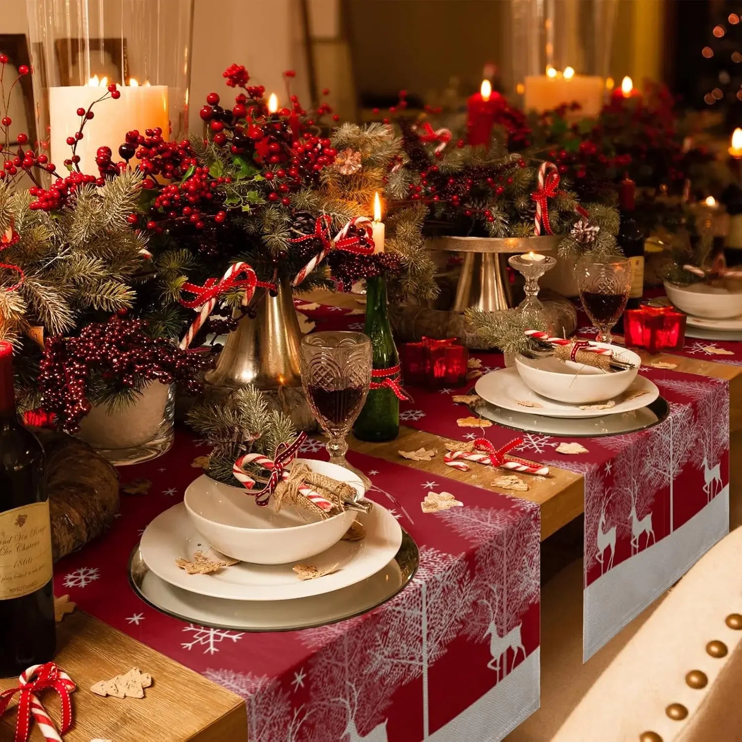 Une table de fête décorée dans un style de Noël avec des bougies allumées, des baies rouges, des branches de pin et des décorations festives.