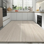 L'image montre une cuisine moderne avec des armoires blanches, un évier avec robinet chromé, un plan de travail en bois clair, et un four encastré. Le sol est recouvert d'un revêtement en bois beige clair, créant une ambiance élégante et épurée.