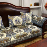 Un canapé en bois foncé avec des coussins décorés de motifs floraux multicolores, créant une atmosphère chaleureuse et élégante dans la pièce.