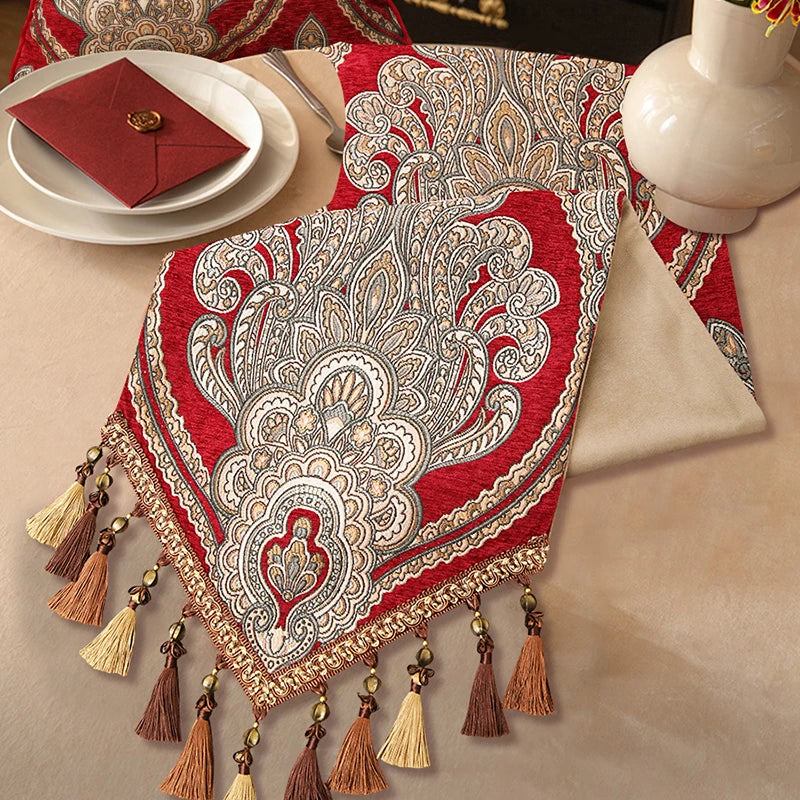 Magnifique nappe rouge ornée de motifs floraux détaillés et de glands dorés, créant un élégant et chaleureux décor de table.