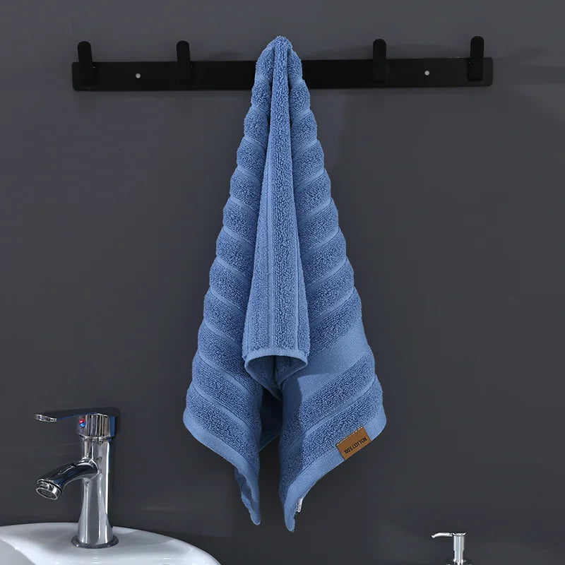 Un élégant porte-serviette noir soutient fermement une serviette de bain douce et rayée de couleur bleu ciel, prête à être utilisée dans la salle de bain.