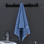 Un élégant porte-serviette noir soutient fermement une serviette de bain douce et rayée de couleur bleu ciel, prête à être utilisée dans la salle de bain.
