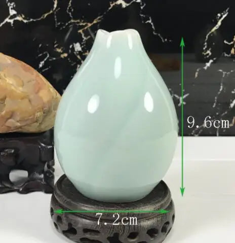 Vase en porcelaine blanche avec socle en pierre sur un fond de marbre noir.