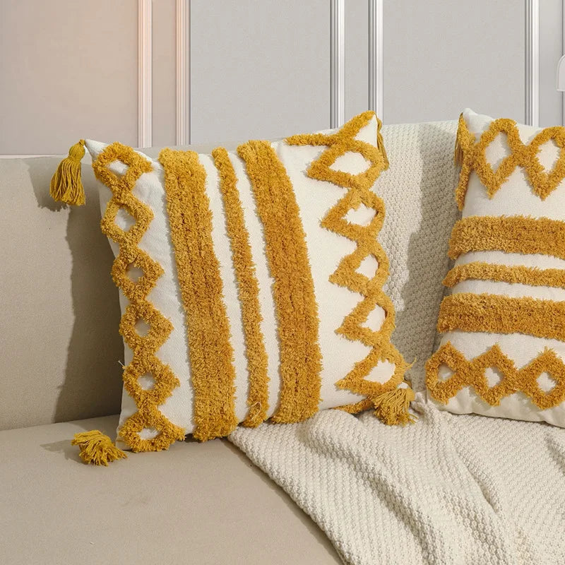 Des coussins aux motifs géométriques jaunes et blancs, avec des franges, apportent une touche décorative et chaleureuse à ce coin de pièce.