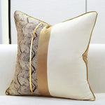 Un coussin décoratif orné de motifs géométriques aux couleurs neutres sur un canapé blanc.