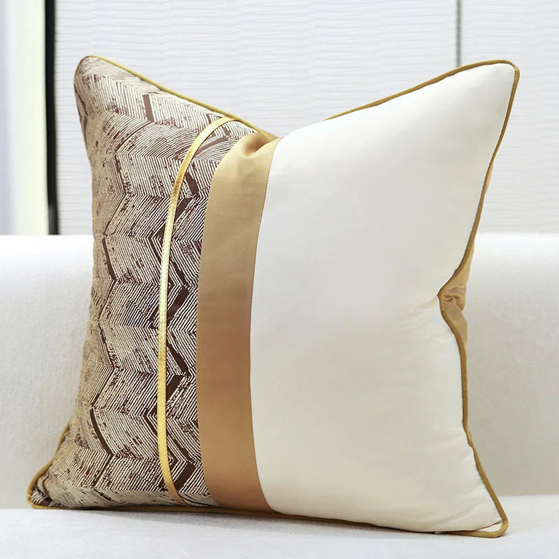 Un coussin décoratif orné de motifs géométriques aux couleurs neutres sur un canapé blanc.