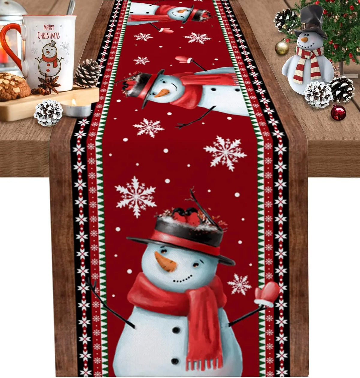 Le chemin de table présente un motif de Noël avec des flocons de neige et un bonhomme de neige portant une écharpe rouge, sur un fond rouge vif.