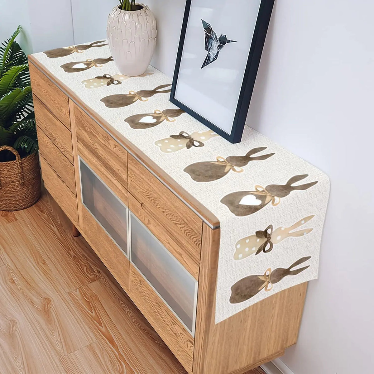 Une commode en bois clair avec un chemin de table décoré de motifs de papillons élégants.