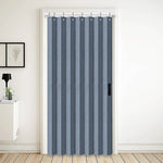 Rideau accordéon bleu gris installé dans une embrasure de porte, utilisé comme cloison souple pour séparer deux espaces de vie avec élégance.