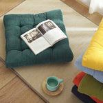 Coussin de sol carré en velours côtelé orange dans un jardin