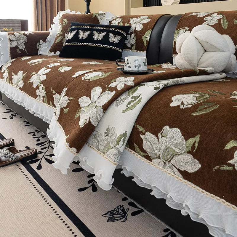 L'image montre une chambre confortable avec un lit douillet couvert d'un couvre-lit marron motif floral blanc et noir, décoré de coussins et d'un ours en peluche, créant une ambiance chaleureuse et accueillante.