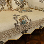 Nappe ornée de motifs floraux et végétaux sur fond crème, avec des franges qui accentuent son élégance.