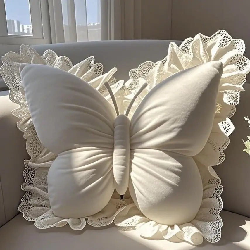 Coussin décoratif en forme de papillon blanc élégant posé sur un drapé raffiné.