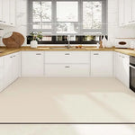 Cuisine moderne avec armoires blanches, comptoirs en bois et éclairage naturel provenant de grandes fenêtres.