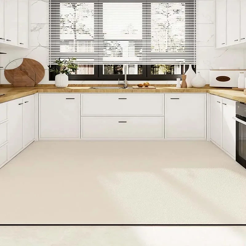 Cuisine moderne avec armoires blanches, comptoirs en bois et éclairage naturel provenant de grandes fenêtres.