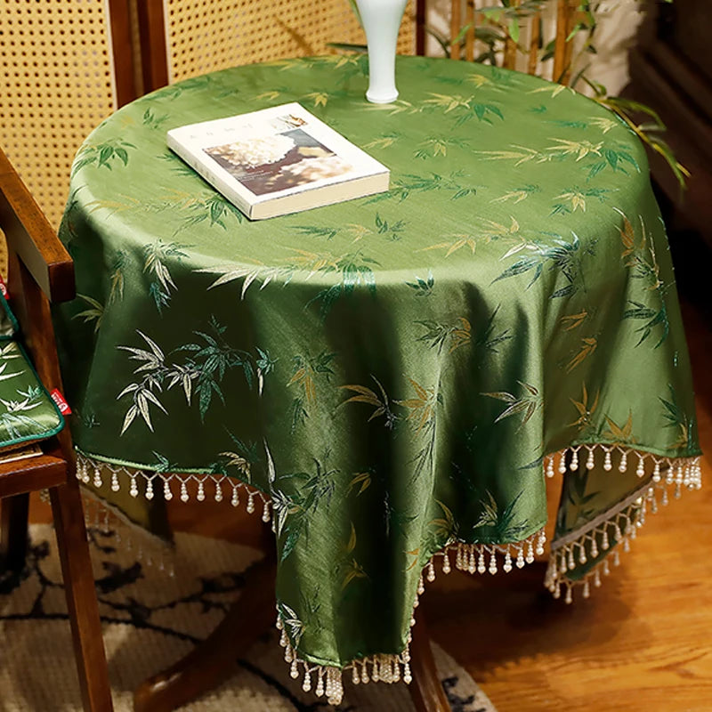Une élégante nappe verte avec un motif de bambous et de grelots décore cette table, créant une atmosphère paisible et raffinée.
