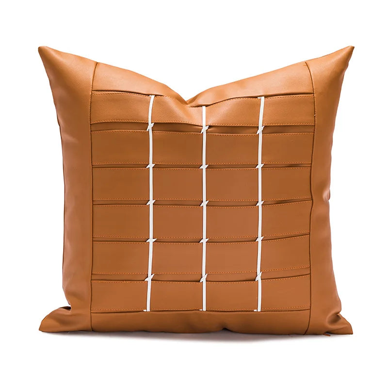 Coussin carré en cuir marron avec motif géométrique en surpiqûres blanches, donnant un style moderne et épuré.