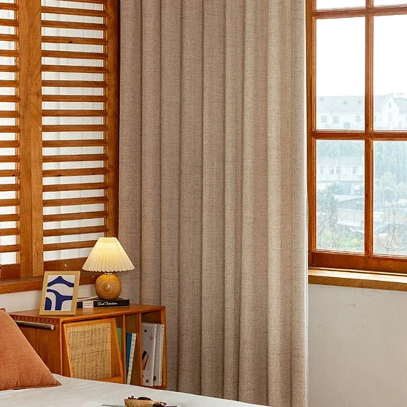Rideau écru à tringle fine installé dans une chambre à l’ambiance bois naturel et lumière douce.