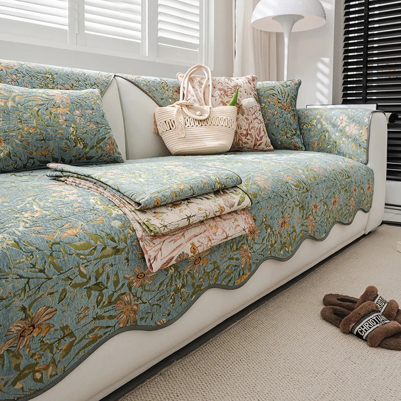 Un canapé luxueusement décoré de coussins, couvertures et accessoires fleuris, créant une ambiance accueillante et sereine dans cette pièce.