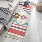 Un tapis coloré aux motifs géométriques décore l'espace, créant une ambiance chaleureuse et accueillante. Le chat gris assis sur le tapis et les pantoufles posées à côté apportent une touche de confort et de douceur à cette scène.