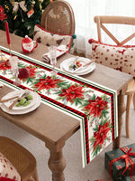Décoration de table de Noël avec des fleurs de poinsettia rouges, des branches de pin, des bougies rouges et des accessoires de table festifs.
