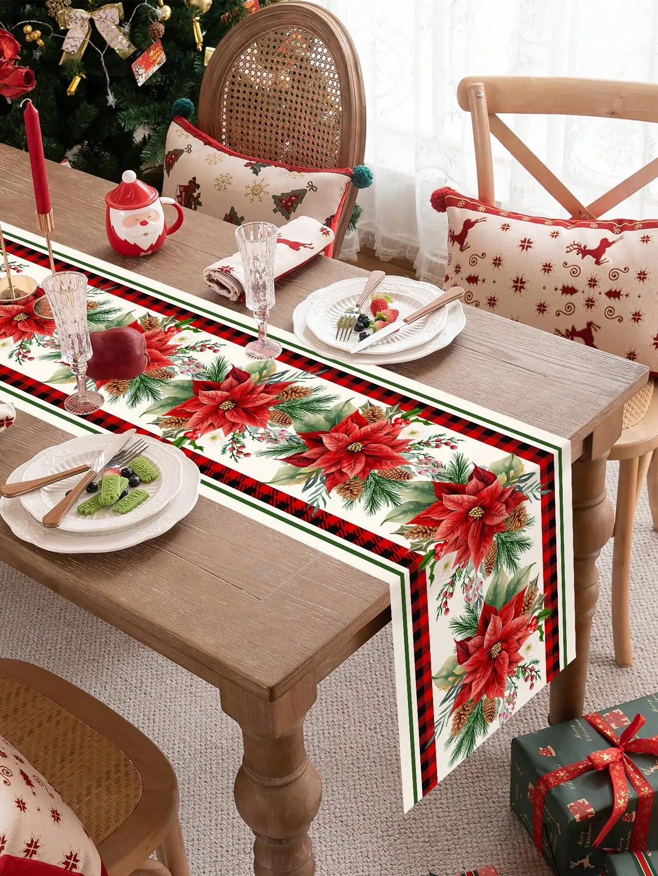 Décoration de table de Noël avec des fleurs de poinsettia rouges, des branches de pin, des bougies rouges et des accessoires de table festifs.