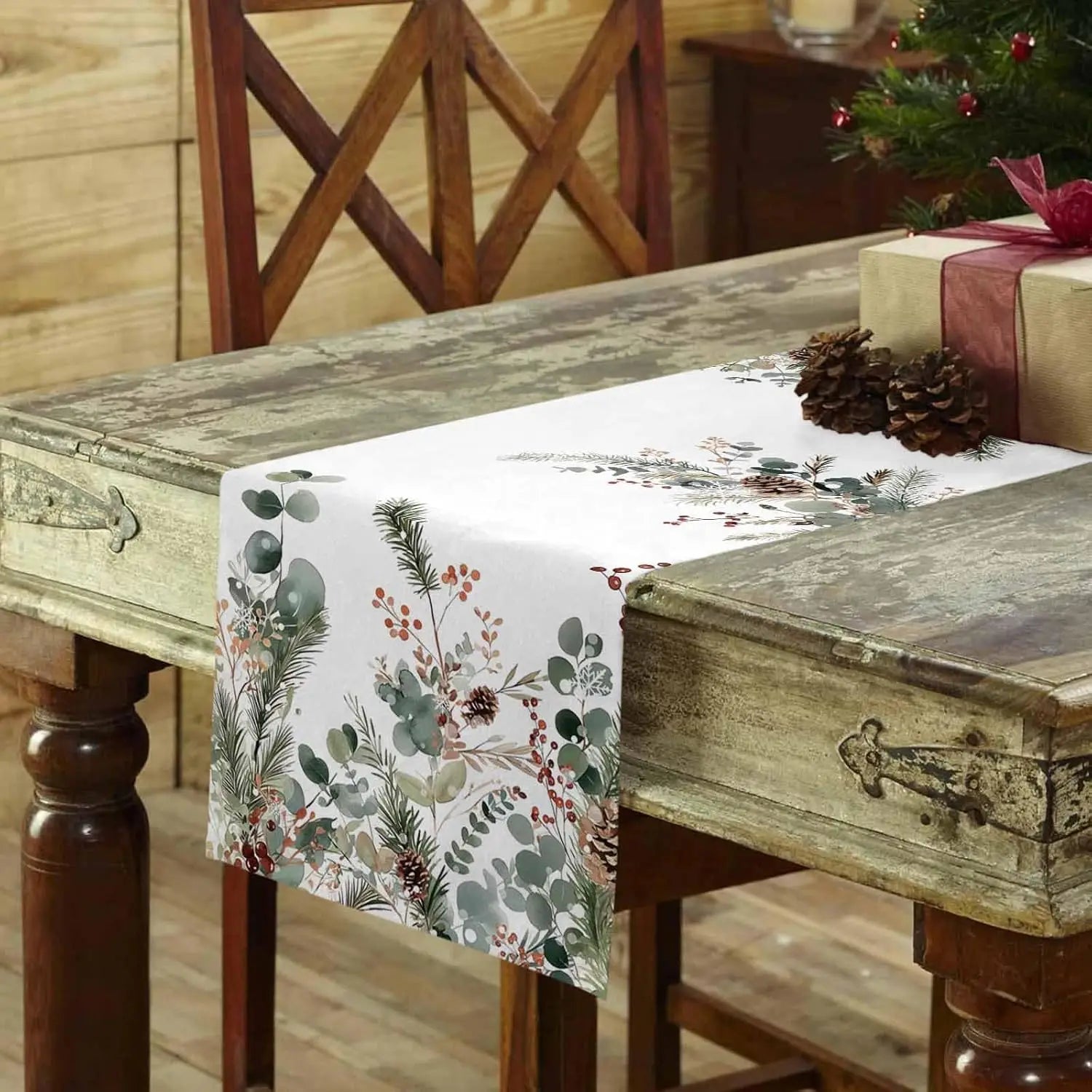 Cette table de salle à manger rustique est décorée d'un élégant chemin de table aux motifs floraux et hivernaux, créant une ambiance chaleureuse et festive pour les fêtes de fin d'année.