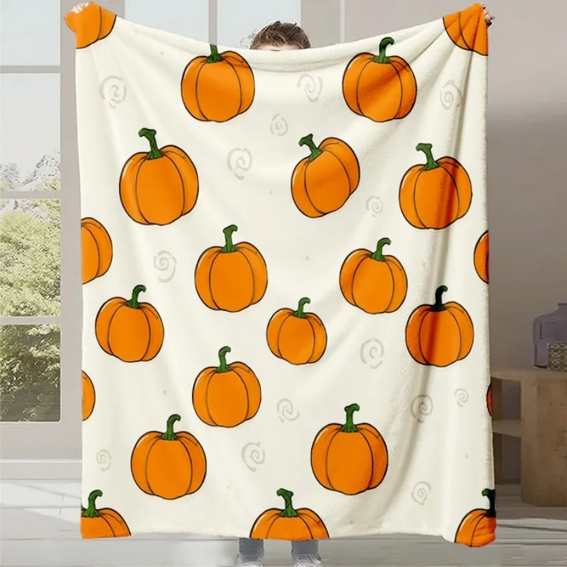 Une couverture blanche ornée de motifs de citrouilles oranges et de spirales.