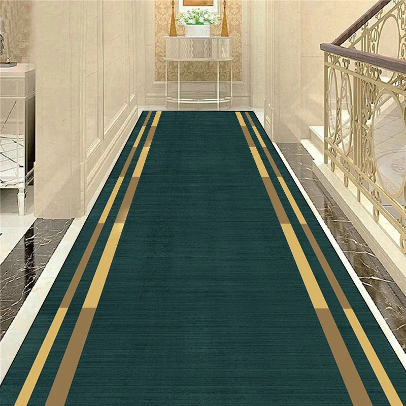 Un long tapis vert avec des bandes dorées, dans un hall d'entrée élégant avec des murs de pierre et une rambarde en métal forgé.