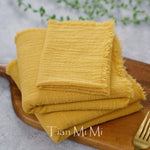 Serviettes en tissu éponge jaune vif, pliées avec soin sur une planche en bois.