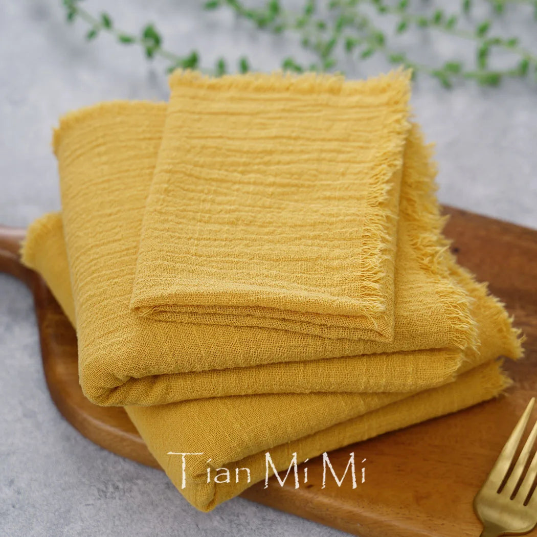 Serviettes en tissu éponge jaune vif, pliées avec soin sur une planche en bois.