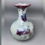 Le vase en céramique présente des motifs abstraits en tons de violet et blanc, créant un design unique et élégant.