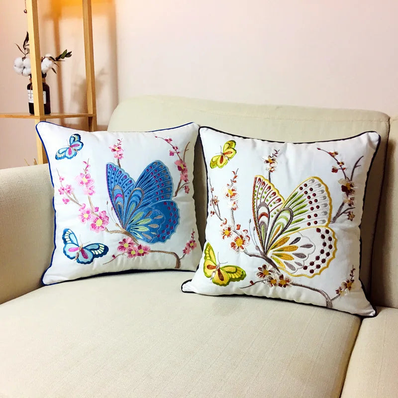 Deux coussins décoratifs ornés de papillons multicolores sur un canapé beige.