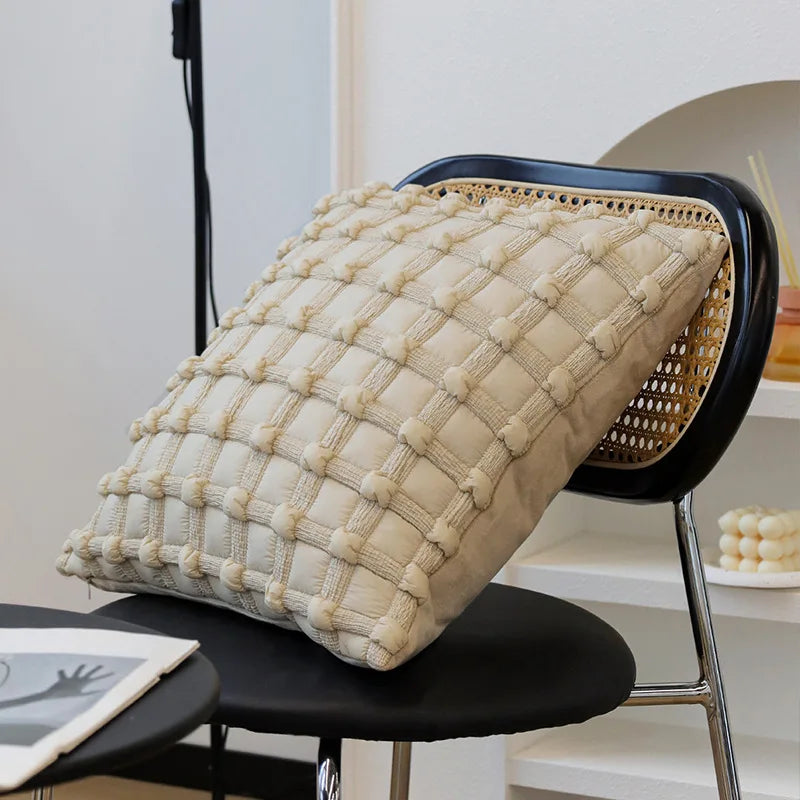 Un coussin texturé beige décoré de motifs en métal sur un siège au design moderne.