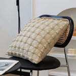 Un coussin texturé beige décoré de motifs en métal sur un siège au design moderne.
