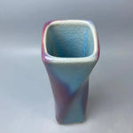 Un vase de design moderne aux couleurs pastel bleu et rose, aux formes géométriques et à la texture craquelée, offrant une esthétique minimaliste et élégante.