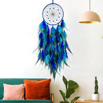 Un attrapeur de rêves décoratif en plumes bleues et vertes avec des détails en métal suspendu au mur.