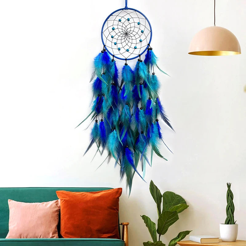 Un attrapeur de rêves décoratif en plumes bleues et vertes avec des détails en métal suspendu au mur.