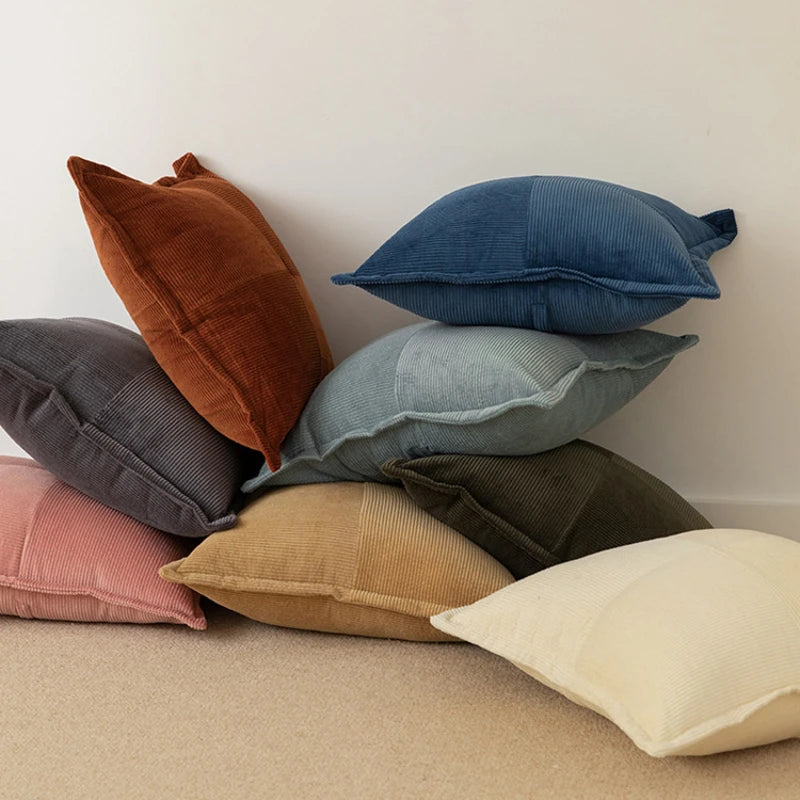 Pile de coussins décoratifs colorés sur un fond blanc, offrant une gamme de textures et de teintes pour ajouter une touche de confort et de style à un espace.