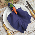 Un couvert de table élégant avec une serviette bleue marine et une décoration végétale sur une table en bois rustique.