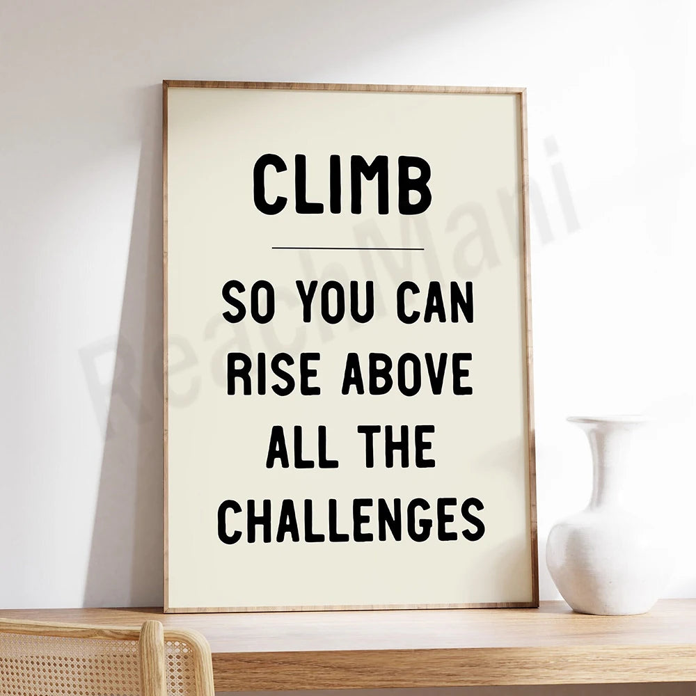 Gravure avec le texte "Climb so you can rise above all the challenges" sur un fond blanc, encadrée dans un cadre en bois.