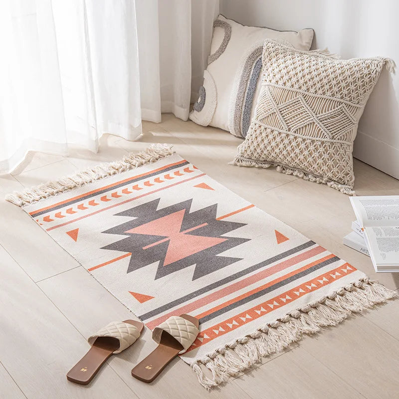 Tapis et coussins décoratifs de style ethnique boho, avec des motifs géométriques et des franges, dans une pièce lumineuse et épurée.