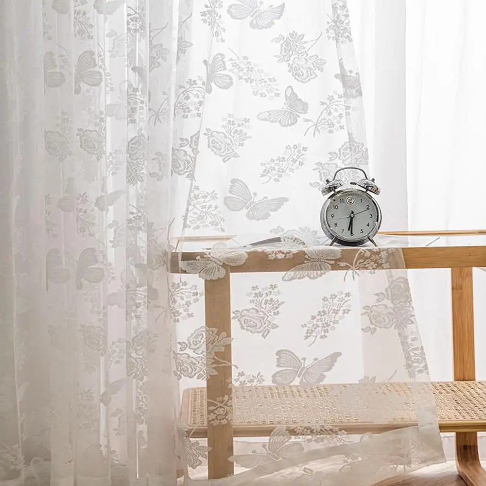 un voilage blanc papillon avec un réveil en argent posé dessus.