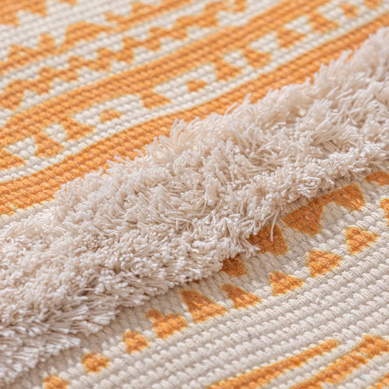 Une couverture en tricot aux motifs géométriques orange et blanc, avec des franges douces et moelleuses.