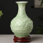 Un vase de porcelaine de couleur verte pastel avec un motif ornemental décoratif représentant des êtres fantastiques.